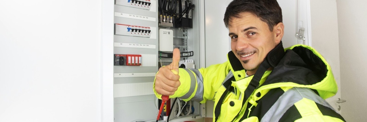 Elektriker vor einem geöffneten Verteilerschrank